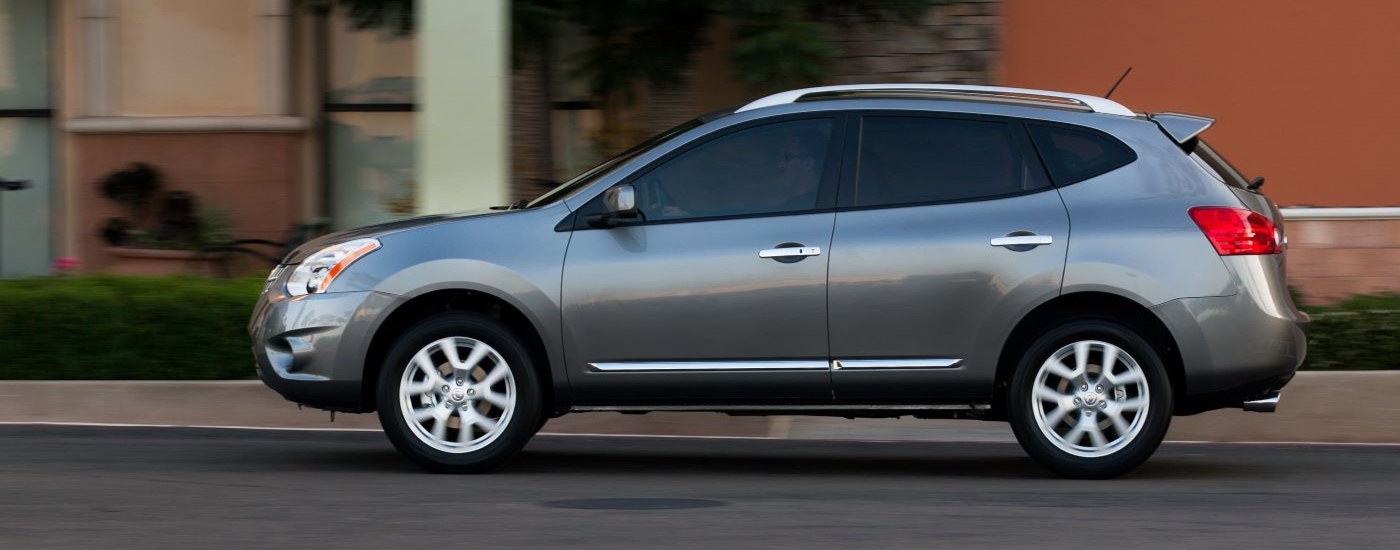 One of the most popular used SUVs for sale, a silver 2012 Nissan Rogue, is shown on a city street.