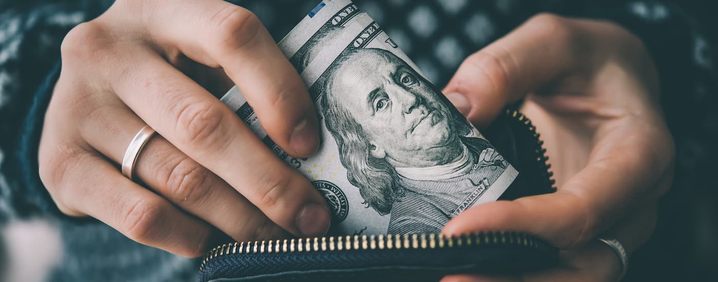 A close up shows a person holding cash.