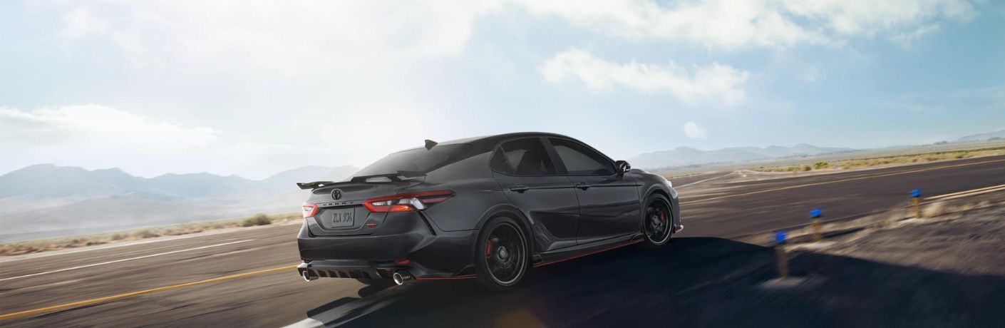 Back view of a black 2023 Toyota Camry on an empty road. 