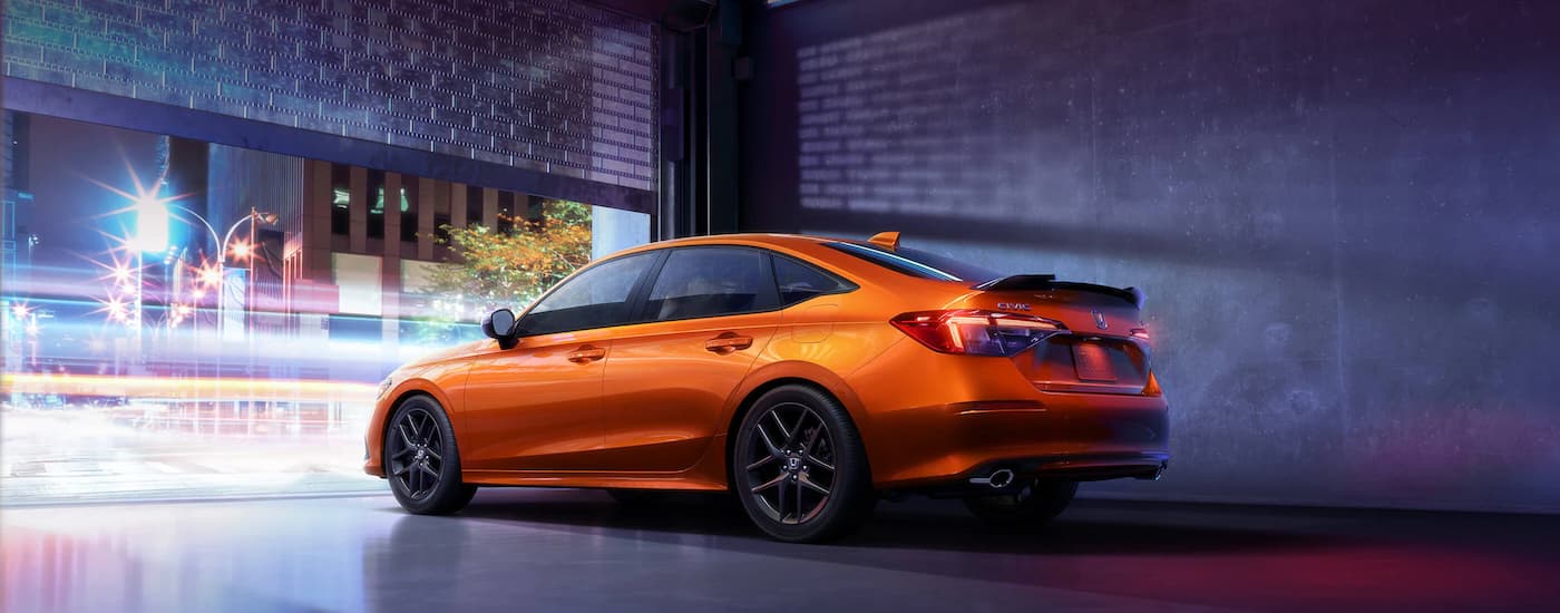An orange 2022 Honda Civic Si is shown leaving a garage.