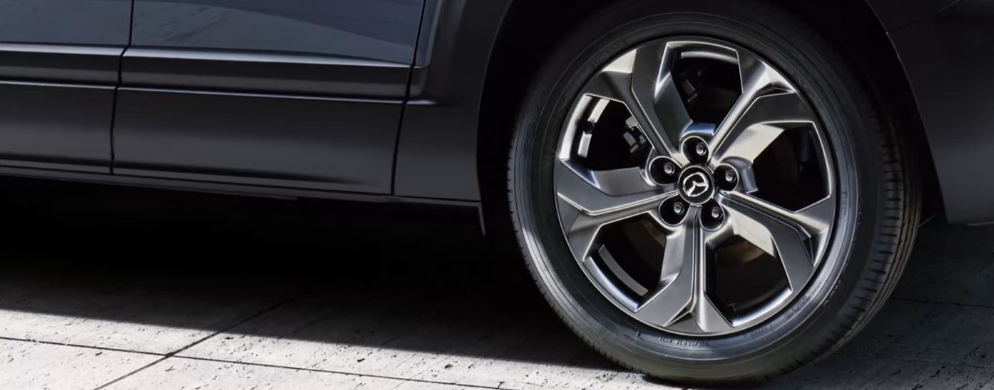 A close up shows a chrome rim on a blue 2023 Mazda MX-30.