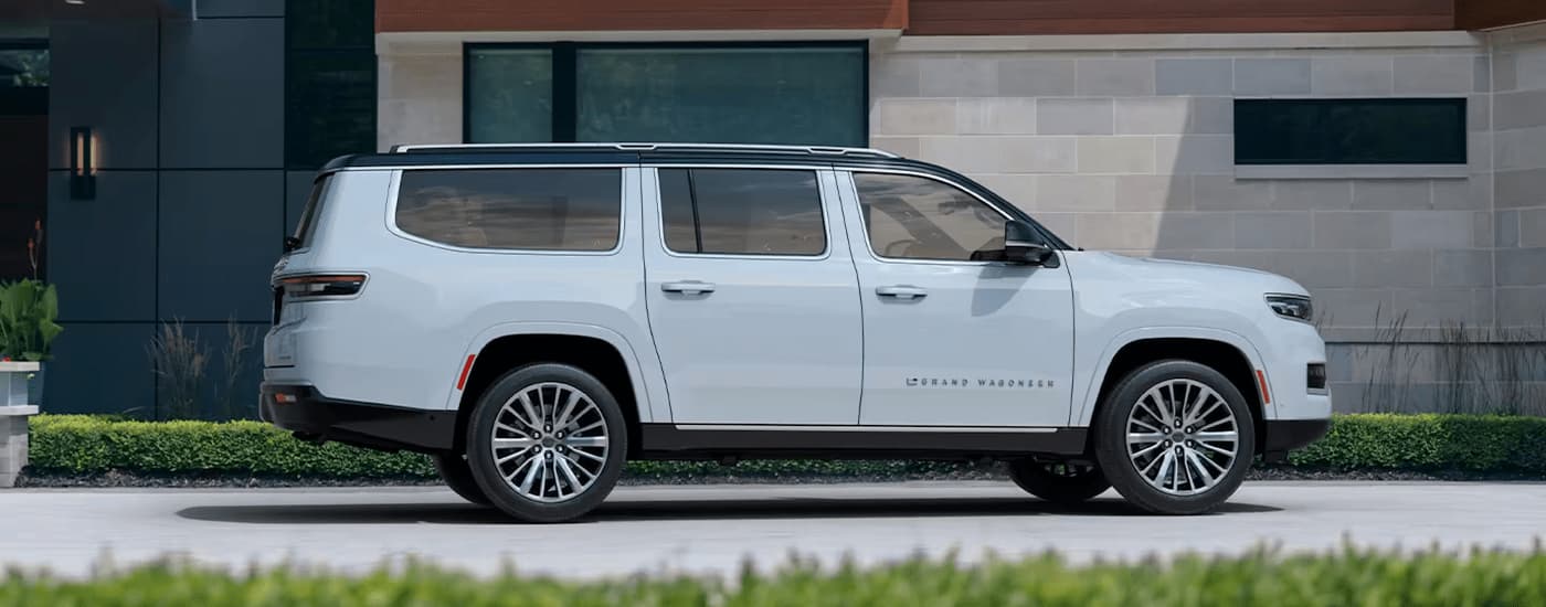 A white 2023 Grand Wagoneer is shown from the side parked on a concrete driveway.