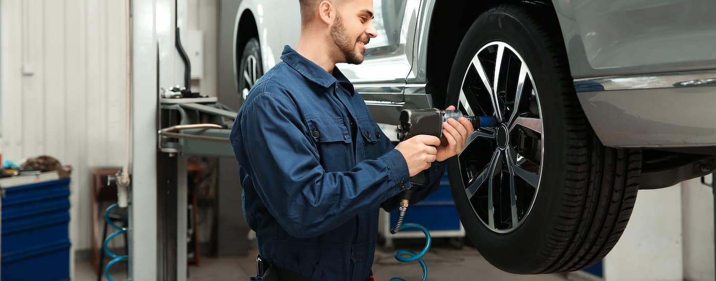 A mechanic performing tire maintenance on a vehicle on a lift.