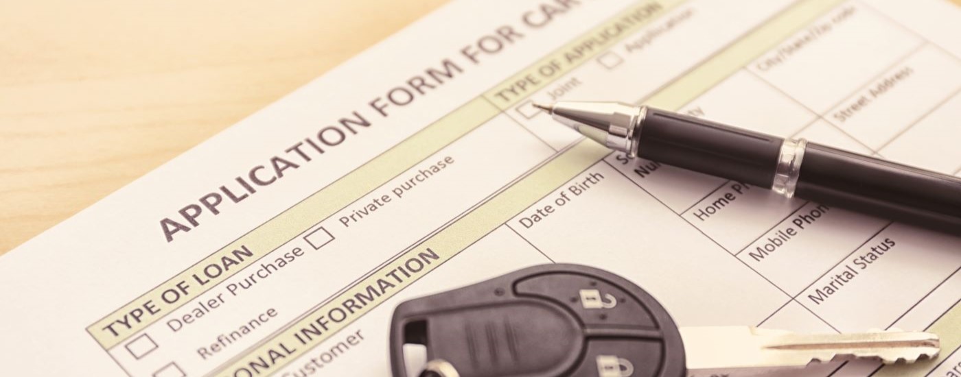 A close up shows a car application, pen, and fob.