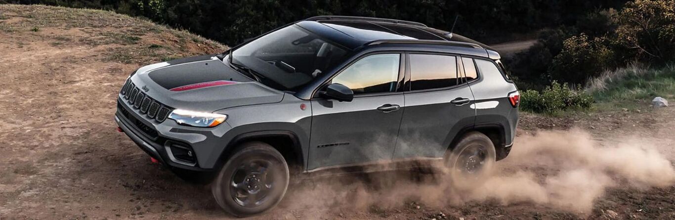 A black 2023 Jeep Compass off-roading during the day.