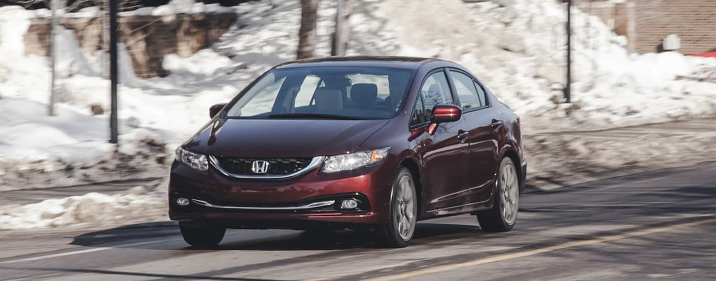 A red 2014 Honda Civic is shown driving on a street with snow in the background.