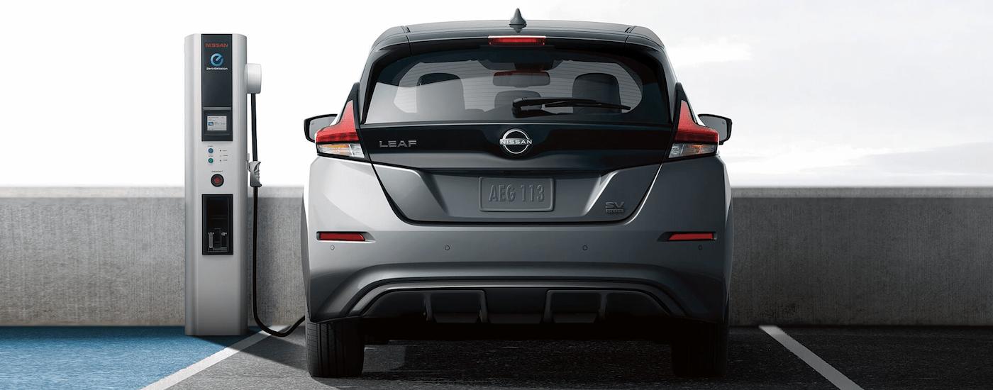 A grey 2023 Nissan LEAF is shown from the rear while parked at a charging station.