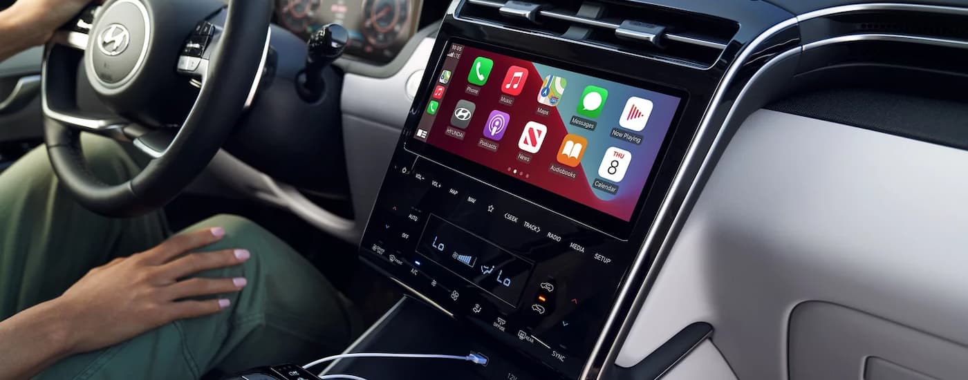 A person is shown using the Apple Carplay feature in a 2024 Hyundai Tucson Hybrid for sale.