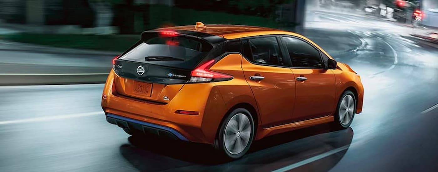 A 2022 Nissan LEAF SL is shown driving on a city street at night.