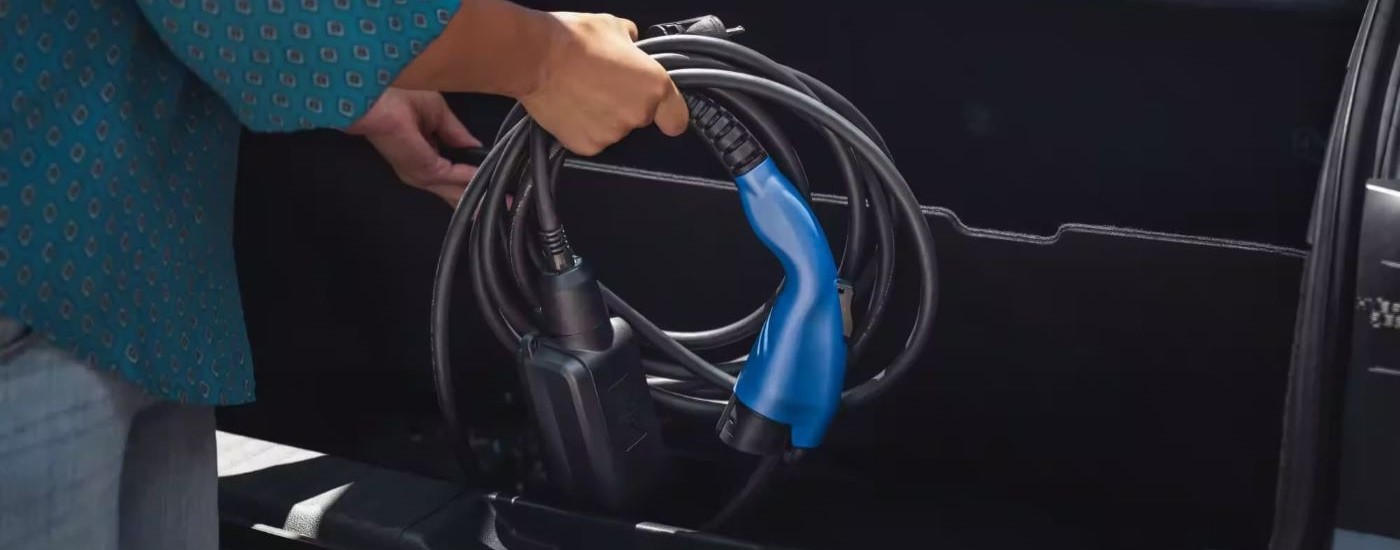 A person is shown stowing the charging cable in a 2023 Toyota Prius Prime XSE Premium.