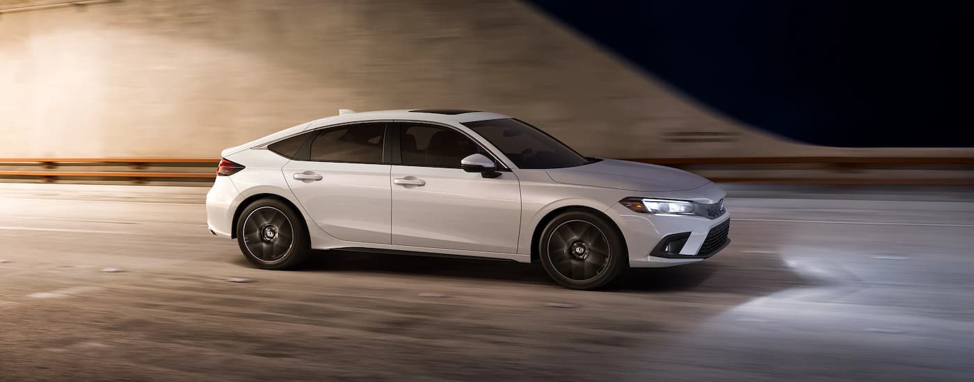A white 2022 Honda Civic Hatchback is shown from the side after leaving a used Honda dealer in Sacramento.