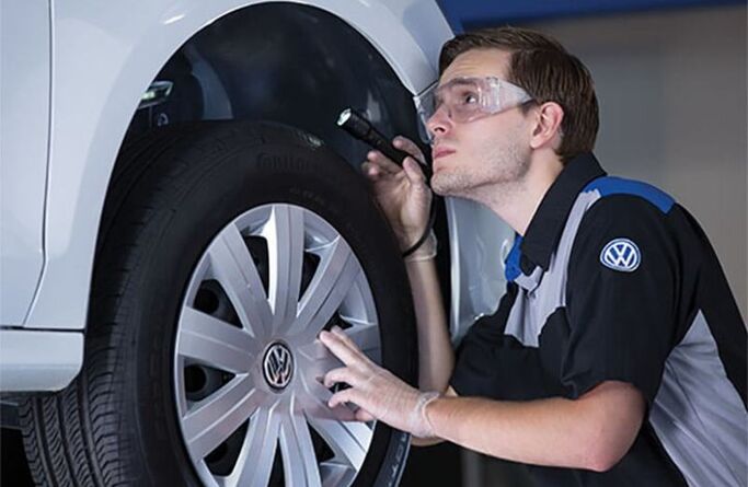 Volkswagen technician inspecting a white Volkswagen vehicle