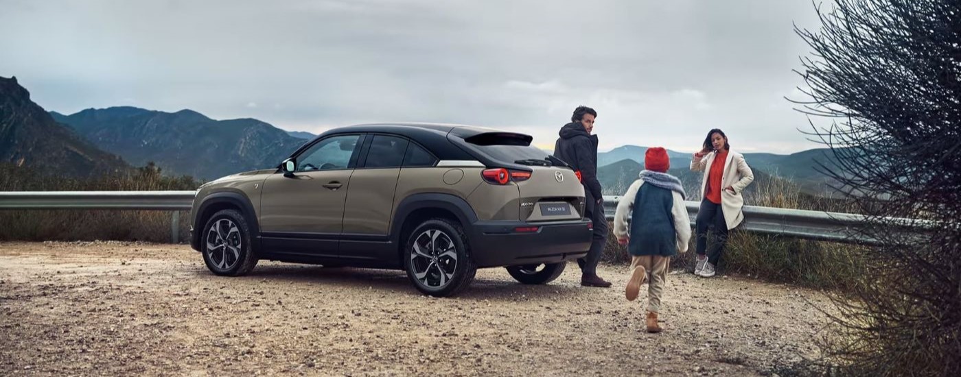 A family is shown near a green  2023 Mazda MX-30.
