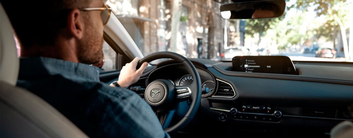 A person wearing sunglasses is shown driving a 2020 Mazda CX-30.