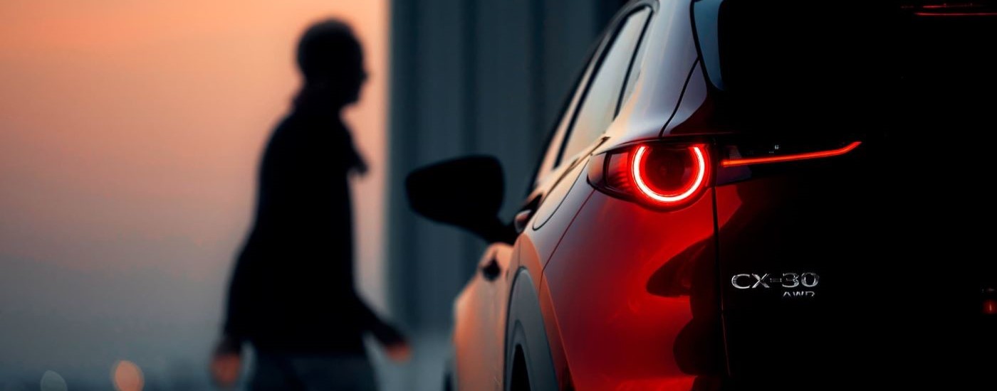 A person is shown walking near a red 2020 Mazda CX-30.