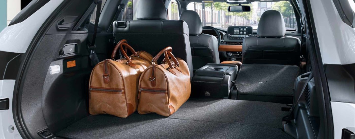 Luggage is shown in the trunk of a white 2023 Mitsubishi Outlander PHEV.