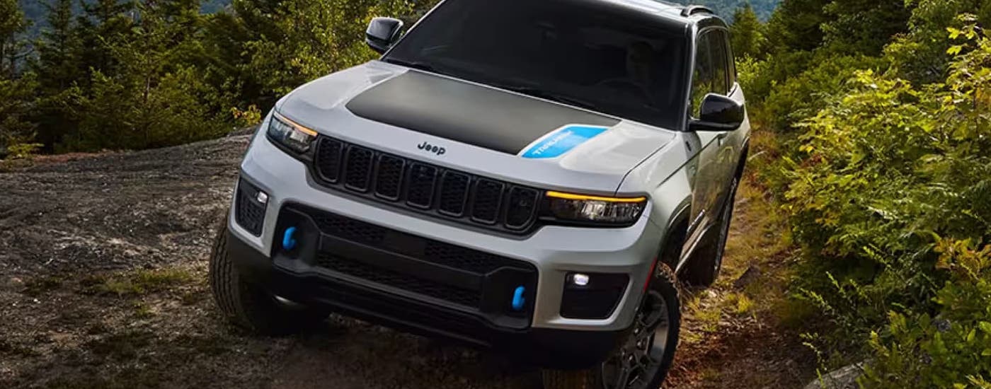 A grey and black 2024 Jeep Grand Cherokee 4xe is shown on a rocky mountain trail.