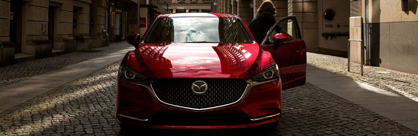 Front angle of a red 2020 Mazda6 with a woman exiting the driver side