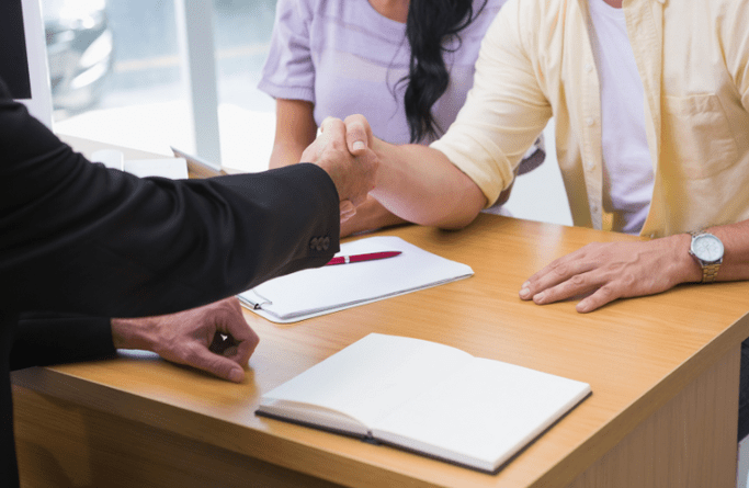 A customer and salesperson shaking hands at a dealership