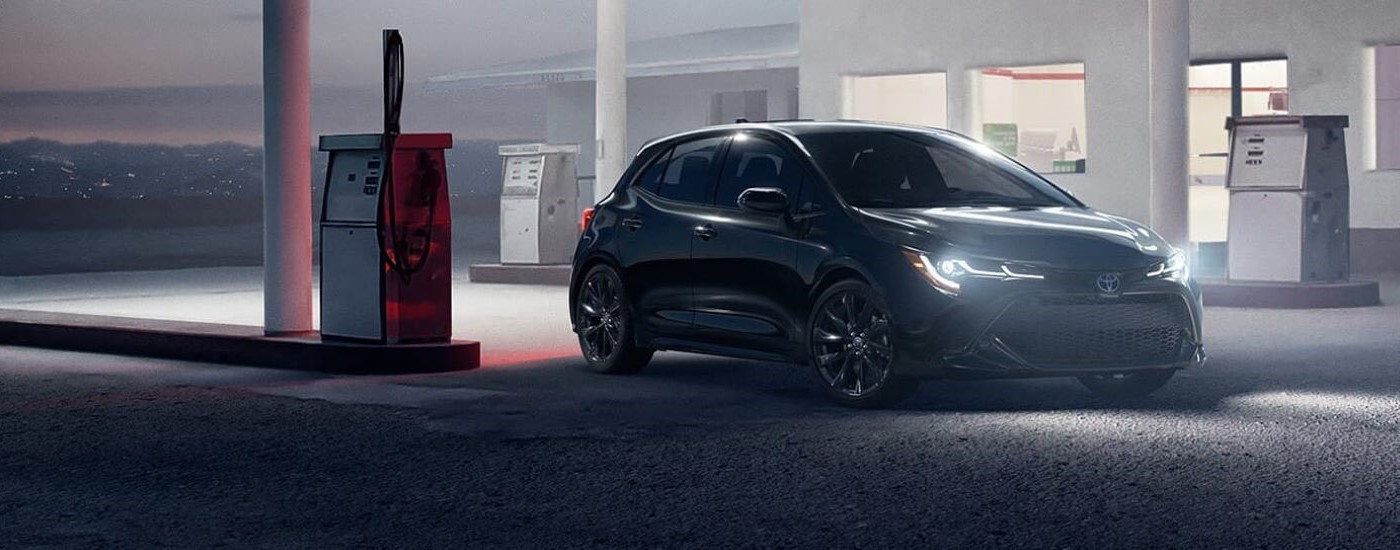 A black 2021 Toyota Corolla is shown parked at a gas station at night.