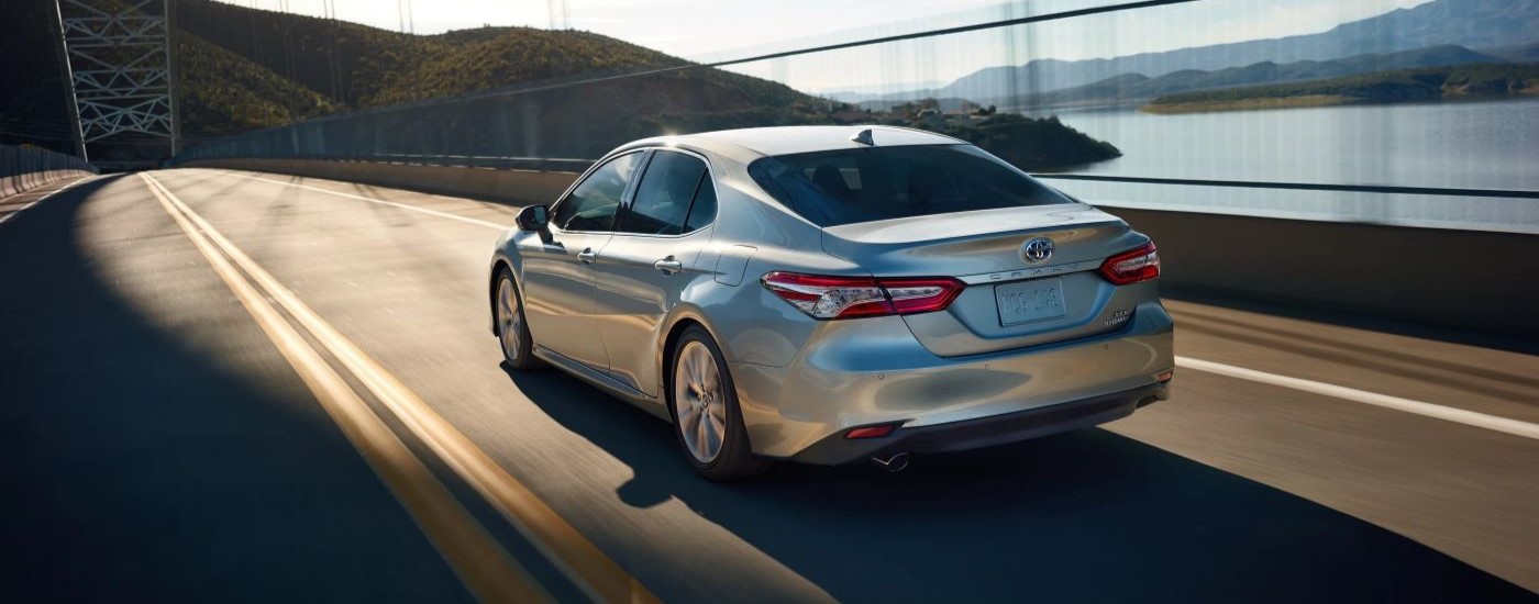 A silver 2020 Toyota Camry XLE Hybrid is shown driving on a bridge.