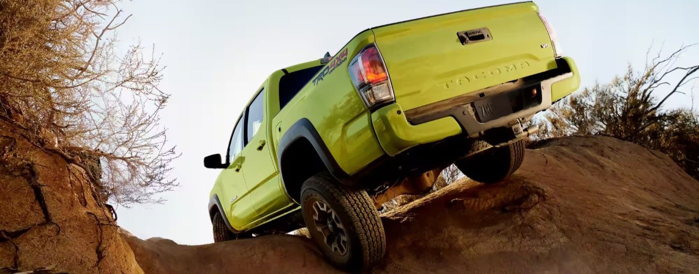 A neon green 2023 Toyota Tacoma TRD is shown from the rear off-roading.