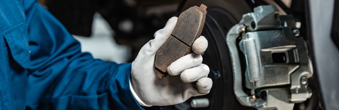Mechanic holding a worn-out brake pad