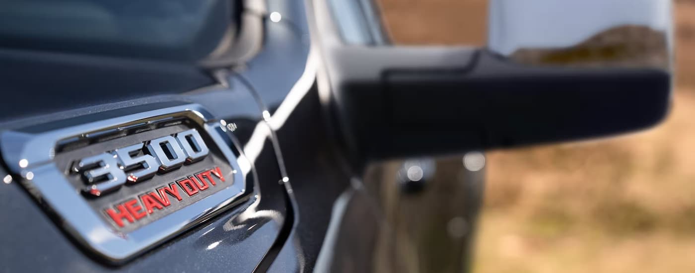 A close up of the hood and side mirror on a black 2023 Ram 3500 HD for sale is shown.