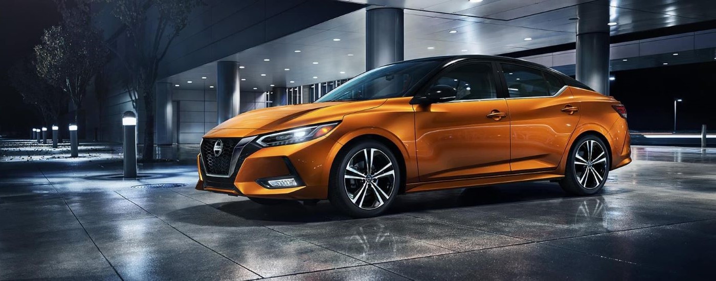 An orange 2021 Nissan Sentra for sale is shown parked at night.