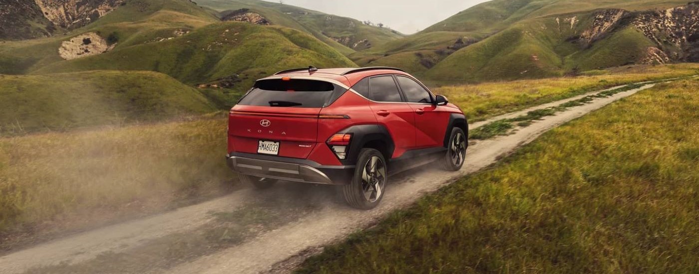 A red 2024 Hyundai Kona Limited is shown from the rear kicking up dust on a trail.