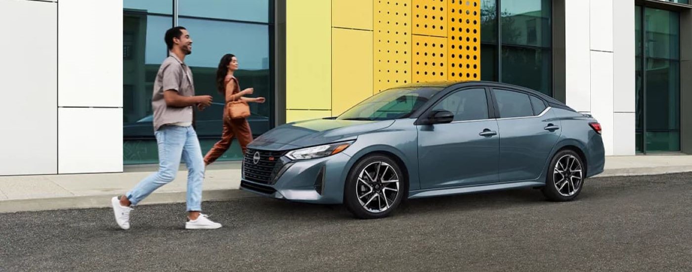 A couple is shown walking toward a grey 2024 Nissan Sentra SR.