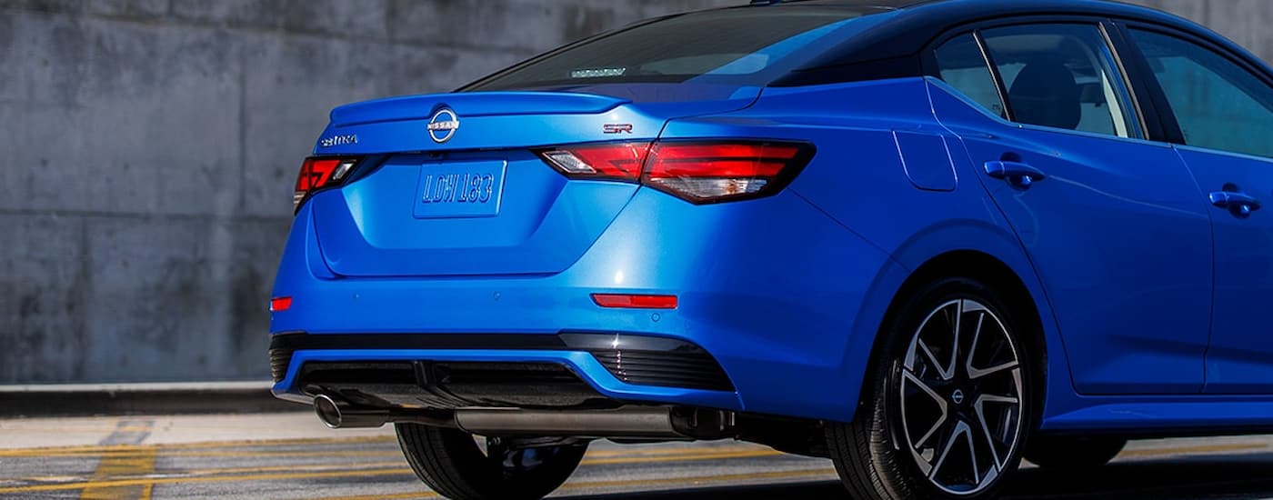 A blue 2024 Nissan Sentra SR is shown from the rear parked in an open lot.