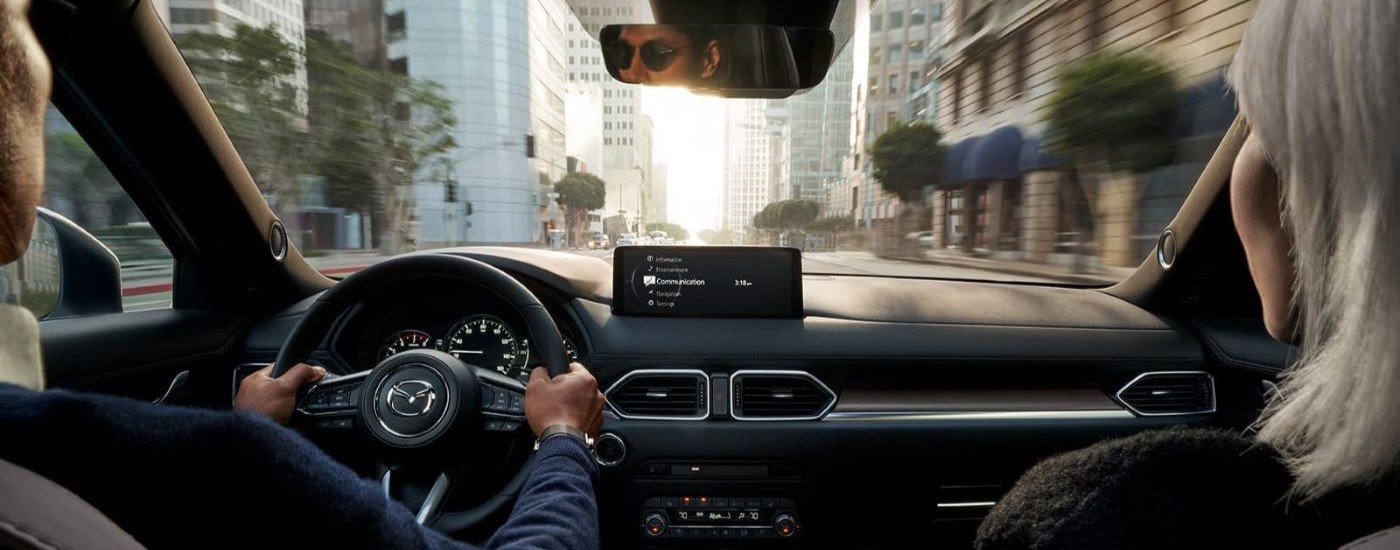 People are shown driving a 2023 Mazda CX-5 on a city street.
