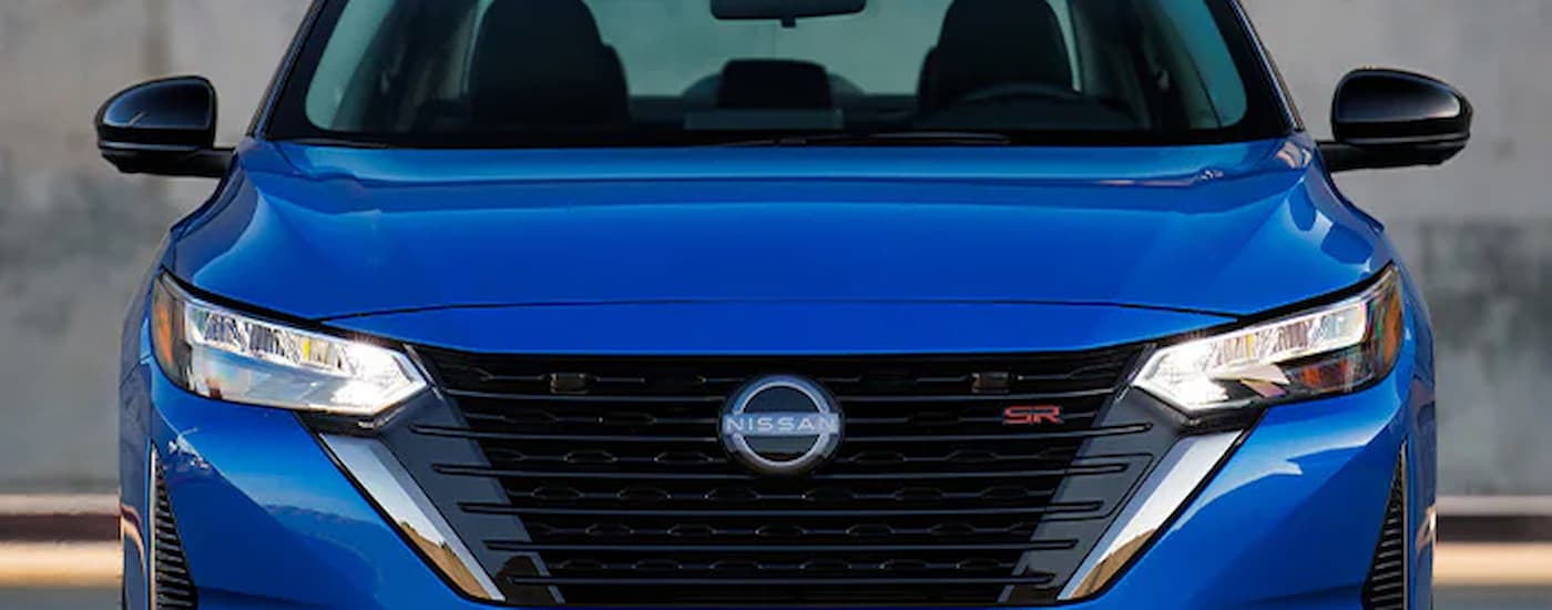 A blue 2024 Nissan Sentra for sale is shown from the front while parked.
