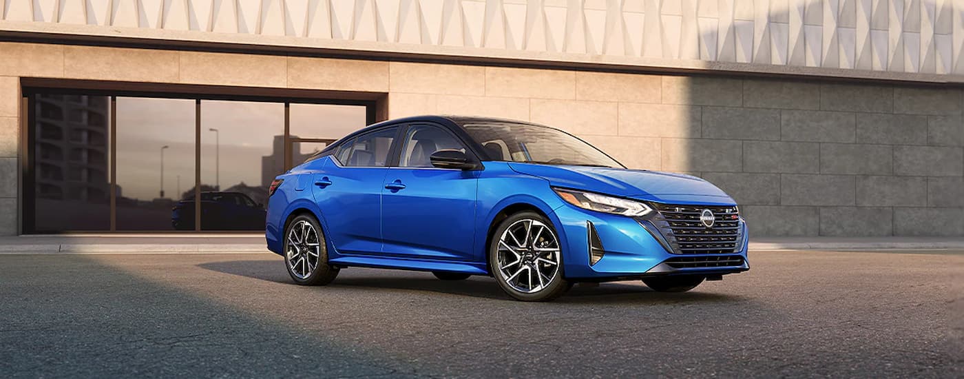 A blue 2024 Nissan Sentra SR for sale is shown parked outside of a dealership.