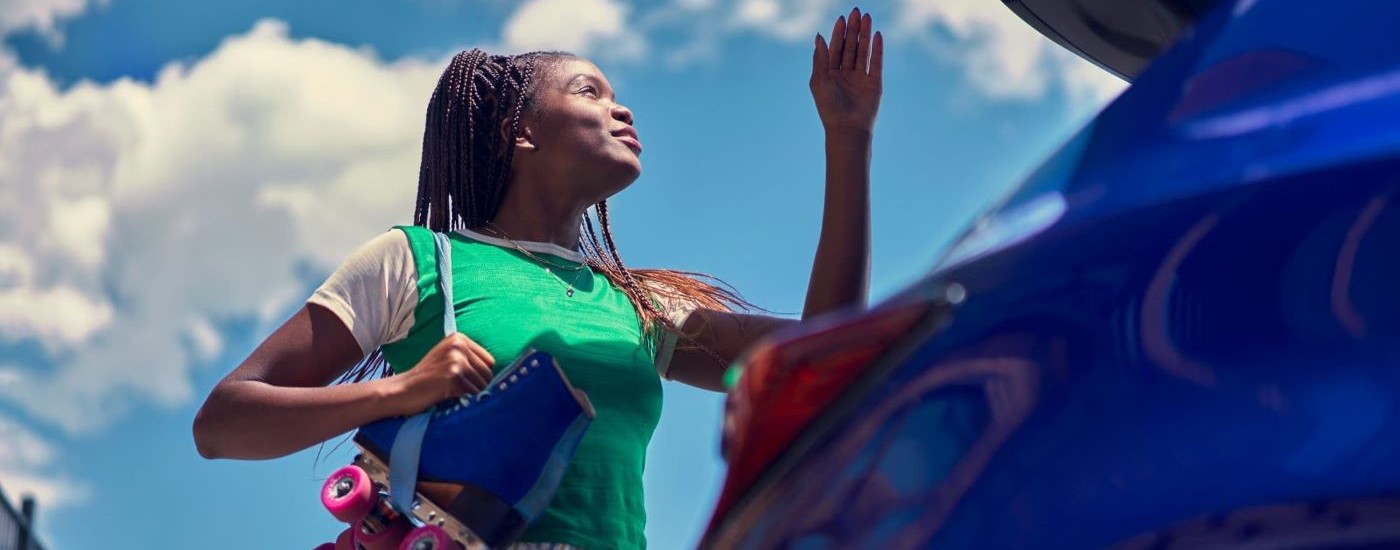 A person with roller skates is shown opening the hatch on a blue 2024 Toyota Corolla.