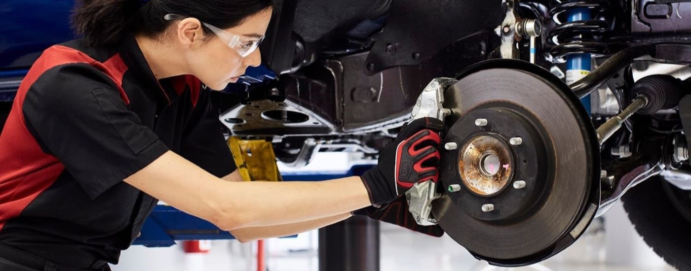 A tech is shown performing a brake service on a blue  2023 Toyota Tacoma.