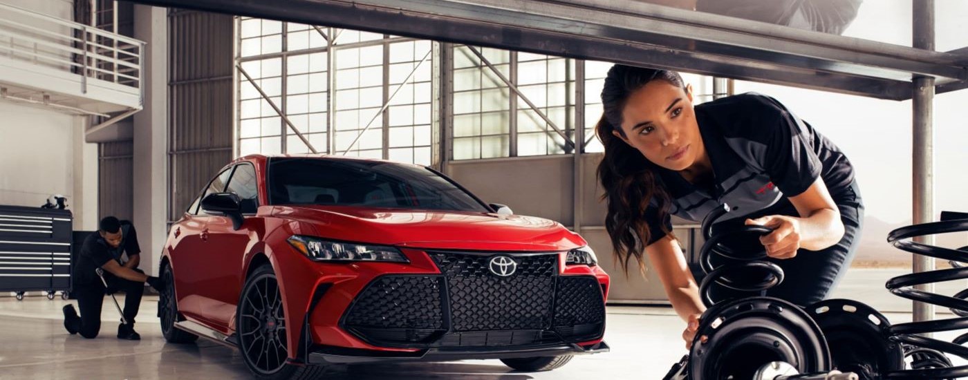 A red 2023 Toyota Camry TRD is shown during a suspension service.