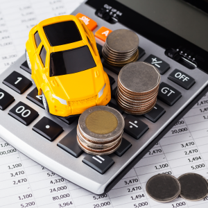 A photo of a toy car and coins on top of a calculator