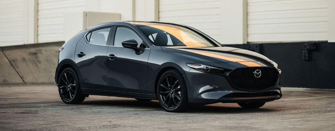 A grey 2023 Mazda3 for sale is shown parked in an empty lot.