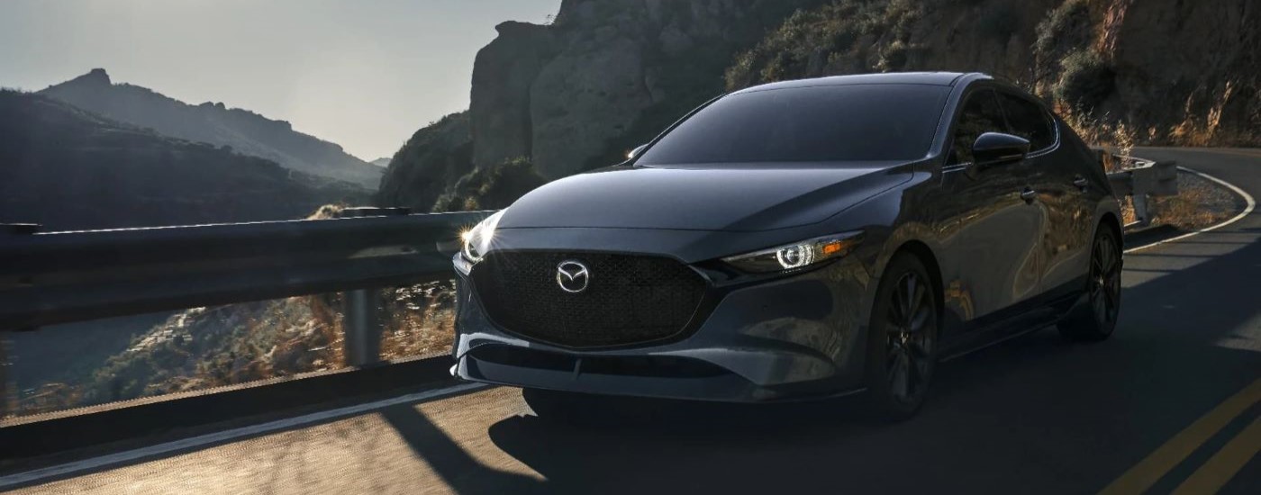 A grey 2024 Mazda3 for sale is shown rounding a corner.