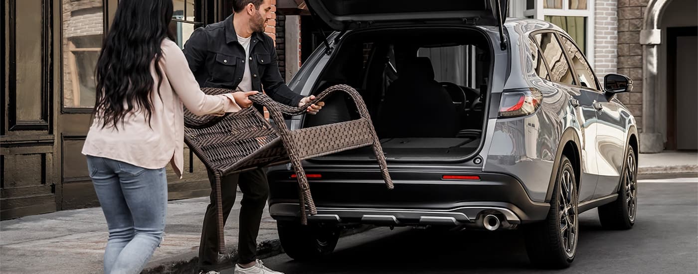 A couple loading a brown wicker chair into the rear storage area of a 2024 Honda HR-V Sport.