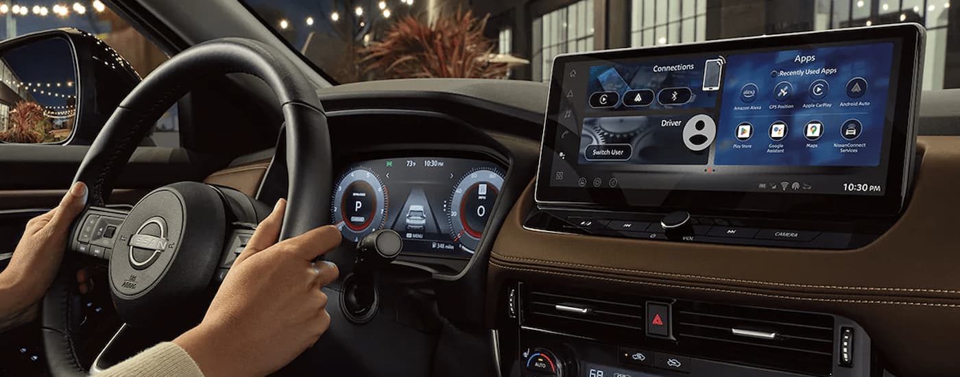 A close up of hands on the steering wheel of a 2024 Nissan Rogue is shown.