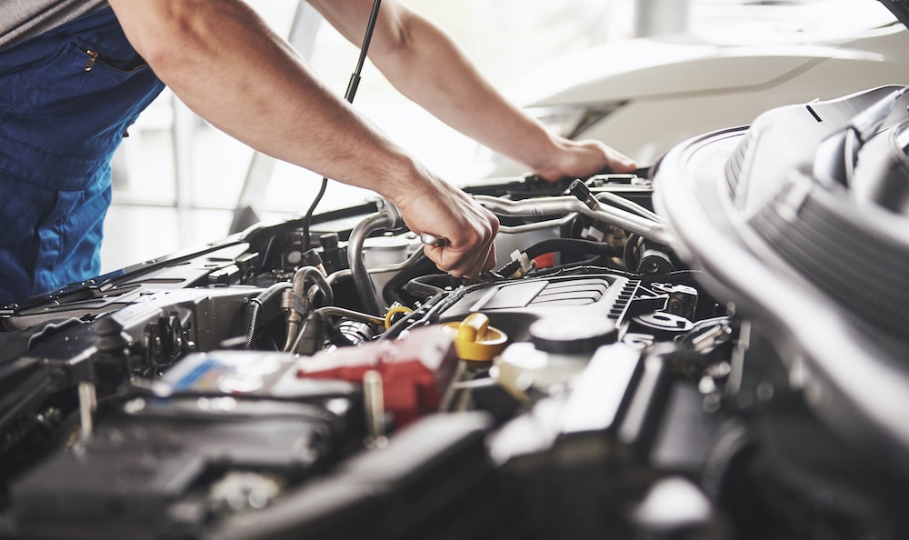 Technician working under car hood