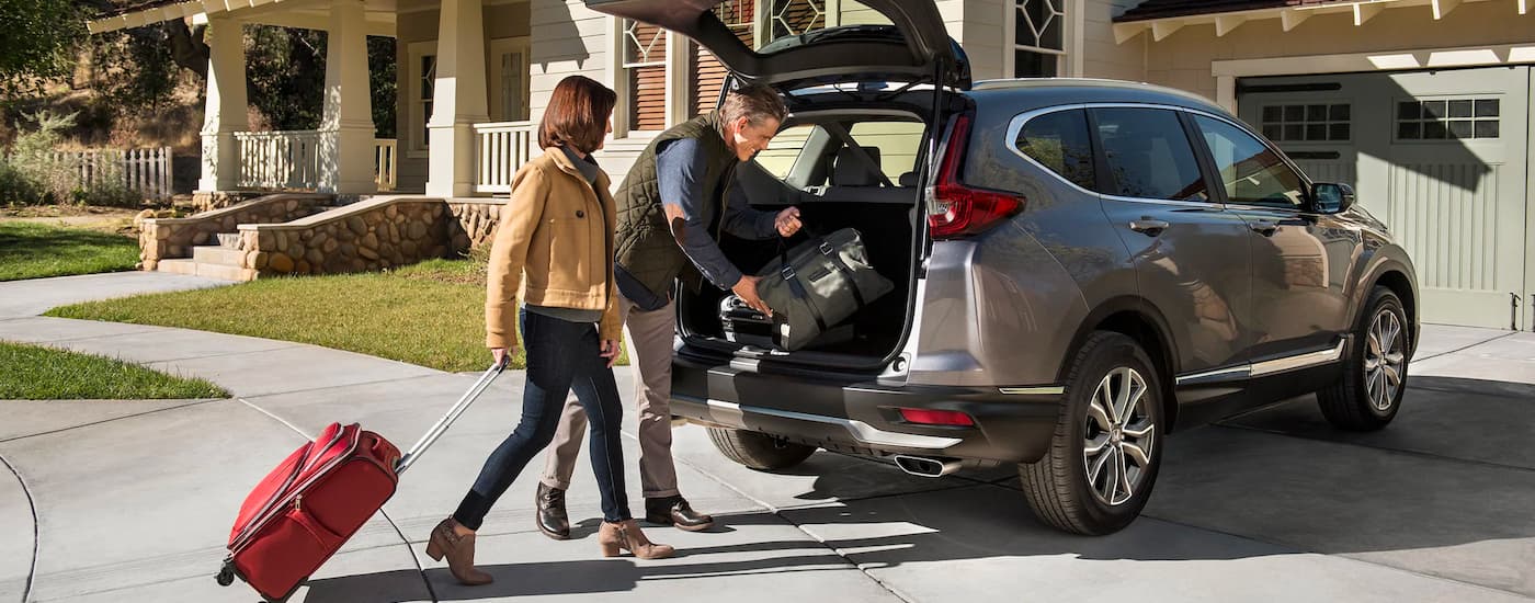 People are shown stowing luggage in the trunk of a 2022 Honda CR-V Touring.