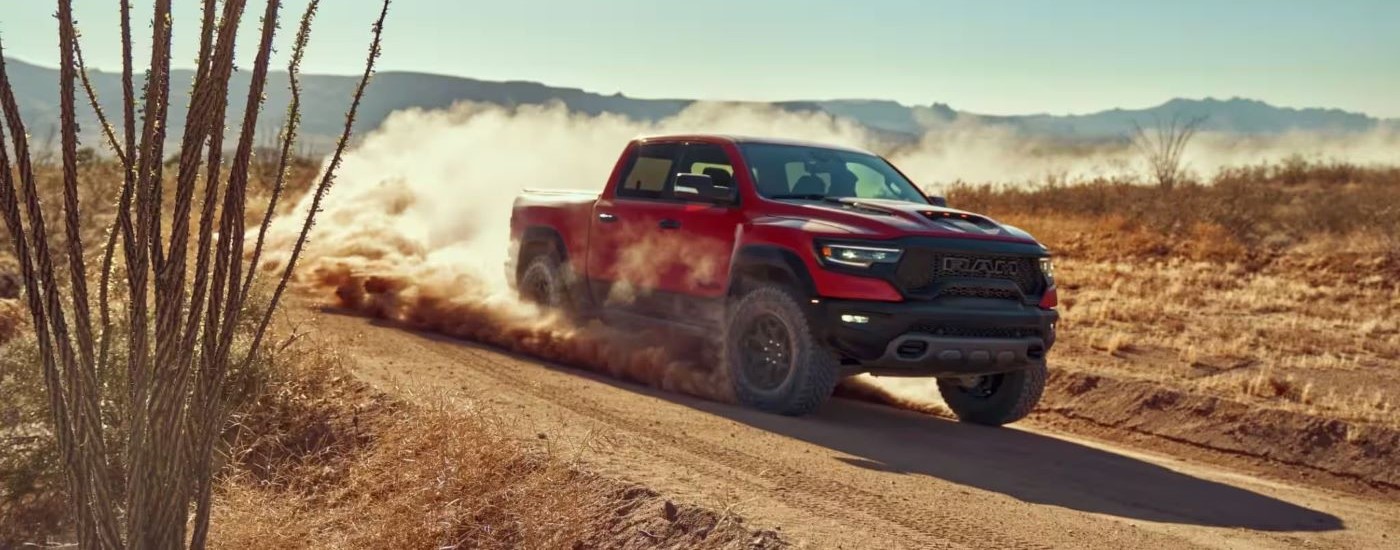 A red 2022 Ram 1500 TRX is shown kicking up dust on a trail.