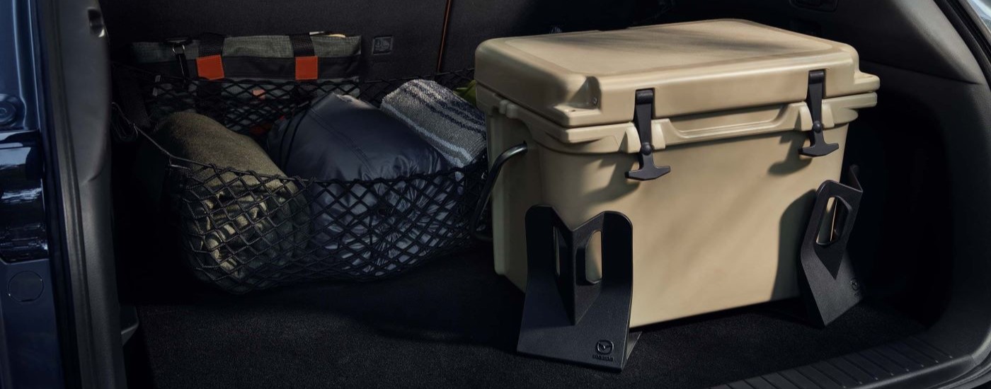 A cooler and sleeping bags are shown in the trunk of a 2023 Mazda CX-50.