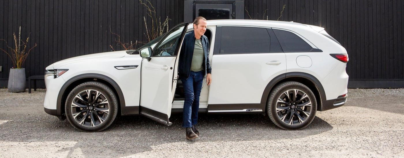 A person is shown exiting a white 2024 Mazda CX-90 PHEV. 