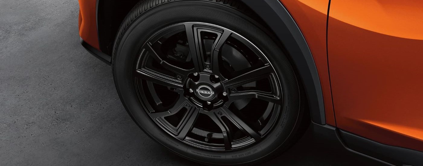 A close up shows a black rim on an orange 2024 Nissan Kicks.