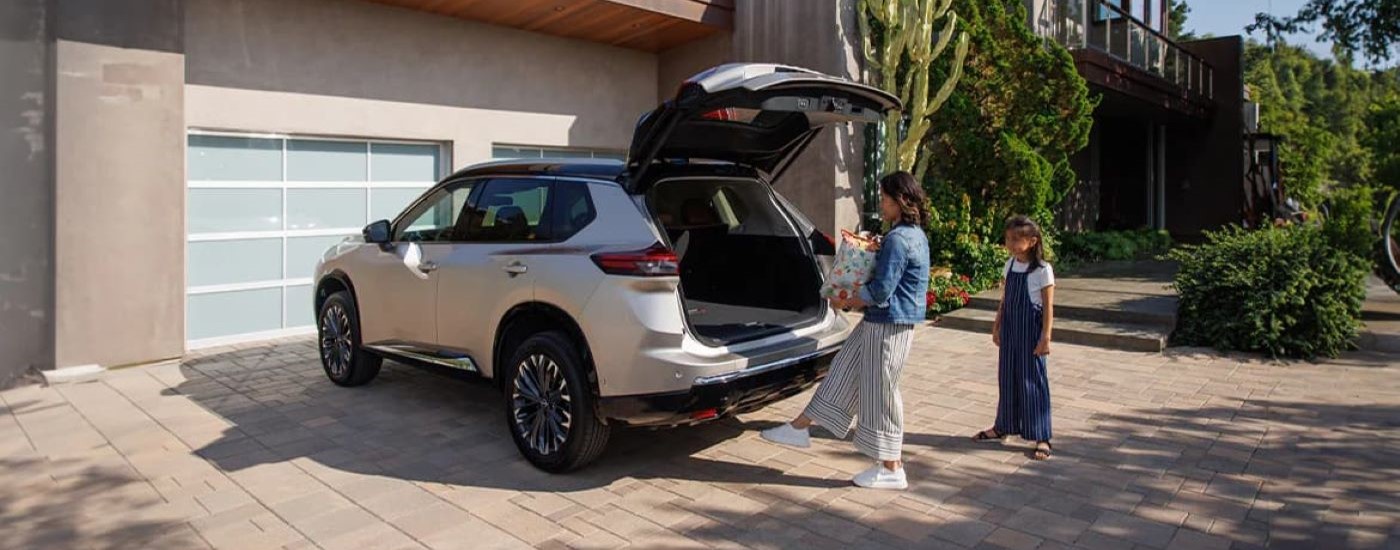 A person is shown loading a bag into a tan 2024 Nissan Rogue.